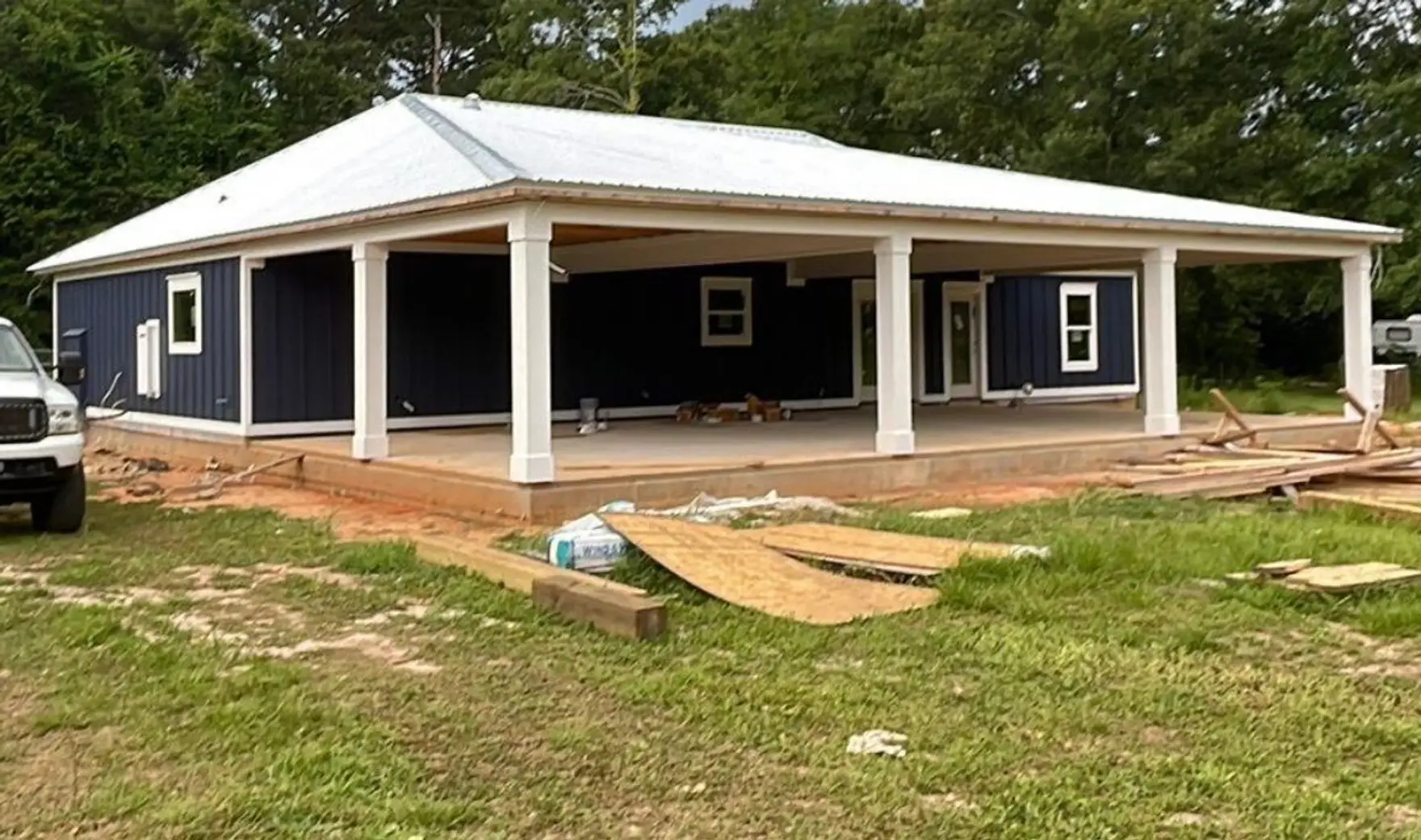 Newly built home under a white low-slope metal roof with a Liberty Roofing Company truck parked in front.