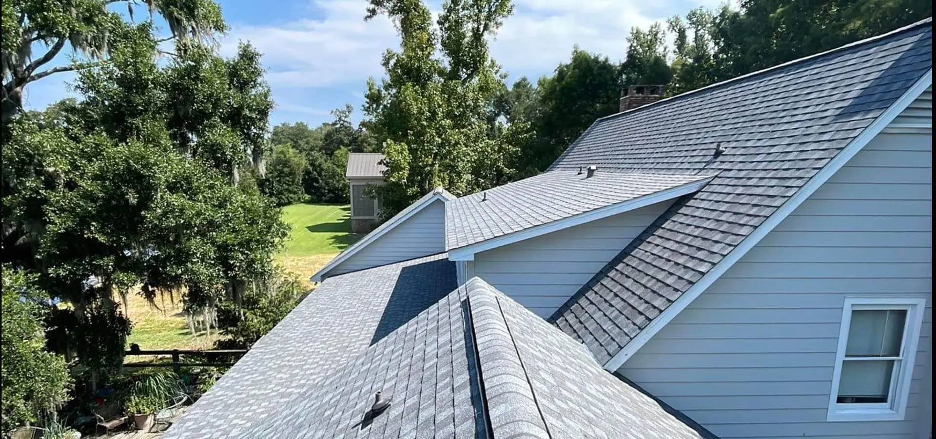Aerial view of a finished gray architectural-shingle roof on a Gulf Coast home under a blue sky.