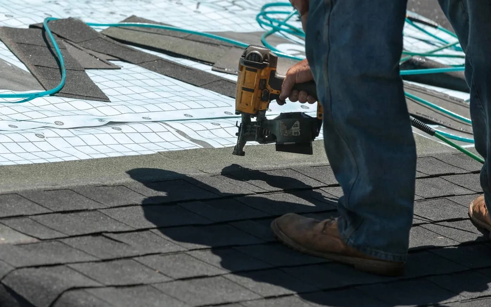 Liberty Roofing crew member nailing down new shingles over synthetic underlayment on a Gulf Coast roof.