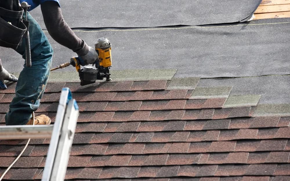 Liberty Roofing crew member nailing new shingle courses over exposed underlayment during a roof repair